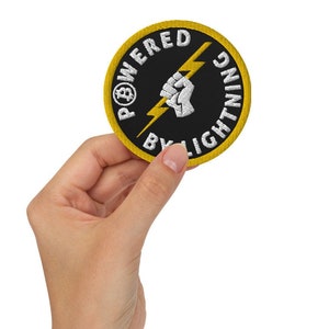 May include: A black and yellow round patch with the text "Powered by Lightning" and a white lightning bolt with a fist holding it.