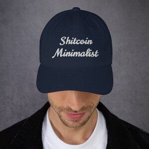 Puede incluir: Una gorra de béisbol azul marino con texto bordado en blanco que dice "Shitcoin Minimalist".