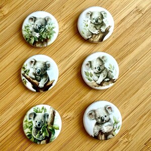 Könnte beinhalten: Sechs runde Kunstwerke mit Koala-Bären. Jedes Stück zeigt eine Illustration im Aquarellstil eines Koala-Bären, einige auf Ästen und andere mit grünem Laub. Die Koalas sind in Grau- und Brauntönen dargestellt.