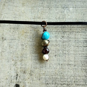 May include: A copper wire wrapped necklace with turquoise, gold, brown, and white beads.