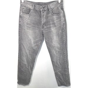 Könnte beinhalten: Graue Jeans aus Denim mit Knopfleiste, Fünf-Taschen-Design und geradem Bein. Die Jeans haben eine einfarbige graue Farbe und scheinen leicht getragen zu sein.