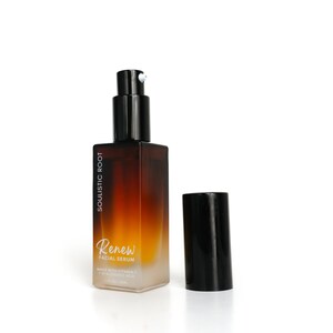 May include: A brown and clear glass bottle of facial serum with a black pump and cap. The bottle has the text "SOULISTIC ROOT" and "Renew FACIAL SERUM" printed on it. The cap is off to the side.