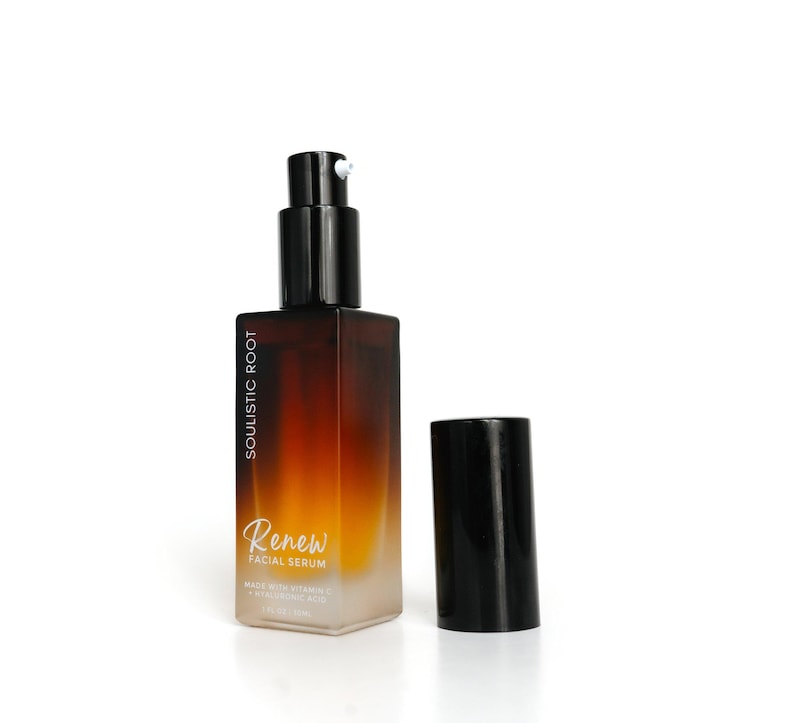 May include: A brown and clear glass bottle of facial serum with a black pump and cap. The bottle has the text "SOULISTIC ROOT" and "Renew FACIAL SERUM" printed on it. The cap is off to the side.