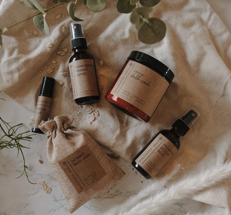K&ouml;nnte beinhalten: Eine Sammlung von Bad- und K&ouml;rperprodukten, darunter ein Eukalyptus-Duschspray, ein entspannendes Kissenspray, ein Haferbad und ein belebendes Bad. Die Produkte werden auf einem hellbraunen Stoffhintergrund pr&auml;sentiert.