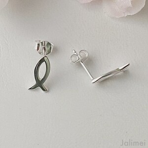 May include: A pair of silver fish-shaped stud earrings. The earrings are small and delicate, and they have a simple, elegant design.