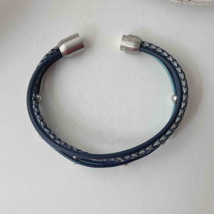 May include: A blue and gray braided leather bracelet with silver magnetic clasps and silver beads.