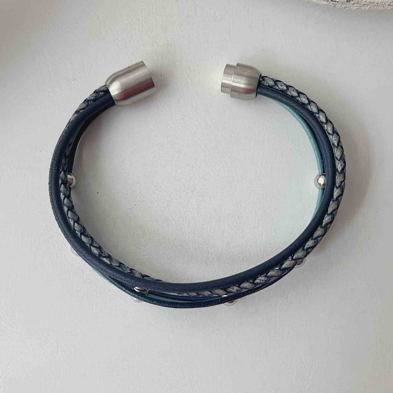 May include: A blue and gray braided leather bracelet with silver magnetic clasps and silver beads.