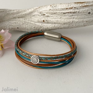 May include: A multi-strand leather bracelet with a turquoise and brown color scheme. The bracelet has a magnetic clasp and a silver charm with a spiral design.
