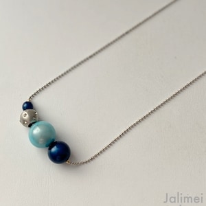Peut inclure: Un collier en chaîne argent avec trois perles. Les perles sont bleues, bleu clair et argent avec de petits strass transparents.