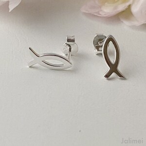 May include: A pair of silver fish symbol stud earrings. The earrings are small and delicate, and they are perfect for everyday wear.