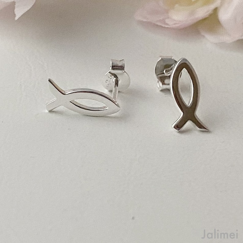 May include: A pair of silver fish symbol stud earrings. The earrings are small and delicate, and they are perfect for everyday wear.