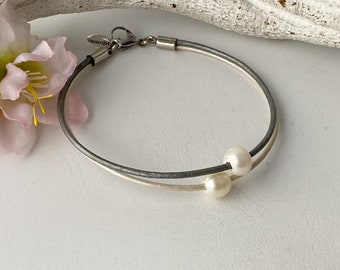 Bracelet composé de 2 lanières de cuir blanc nacré et gris avec 2 perles