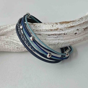 May include: A multi-strand bracelet with blue and gray leather cords and silver beads.