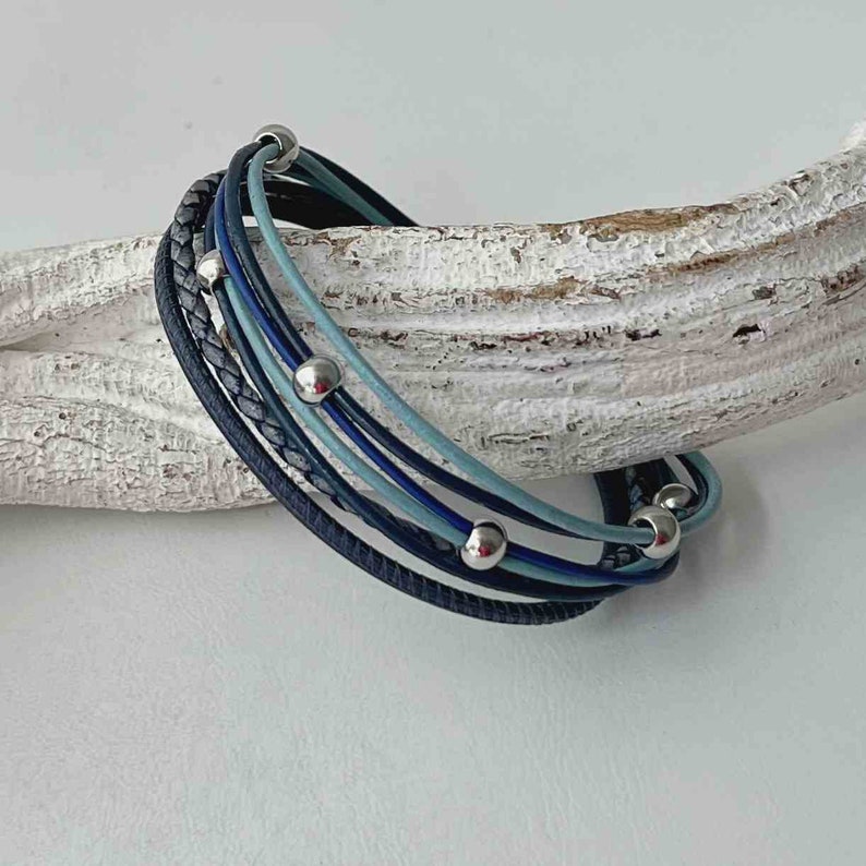 May include: A multi-strand bracelet with blue and gray leather cords and silver beads.