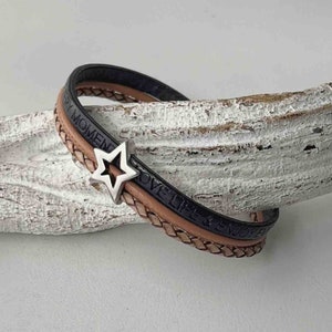 May include: A triple-wrap leather bracelet with a silver star charm. The bracelet is made of black, brown, and tan leather and has the words "Love Life & Enjoy Every Moment" embossed on it.