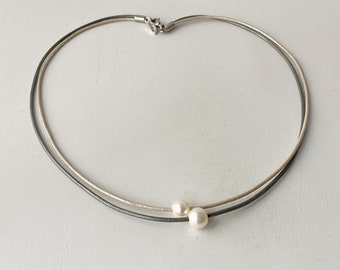 Collar corto hecho de cordones de cuero con 2 cuentas de nácar gris.