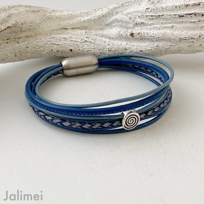 May include: A multi-layered blue leather bracelet with a silver magnetic clasp and a silver spiral charm.