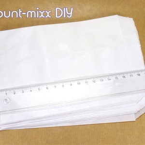 K&ouml;nnte beinhalten: Ein Stapel wei&szlig;er Papiert&uuml;ten mit einem Lineal darauf. Das Lineal ist in Zoll und Zentimetern gekennzeichnet. Die Papiert&uuml;ten sind gefaltet und einsatzbereit.