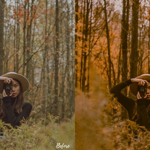 May include: A woman wearing a wide-brimmed hat and a black turtleneck sweater poses in a forest setting. She is holding a camera up to her face and looking through the viewfinder. The trees in the background are mostly bare, with some leaves still clinging to the branches. The ground is covered in fallen leaves and ferns.