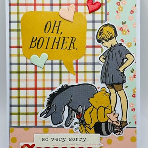 May include: A handmade greeting card featuring illustrations of Winnie the Pooh characters. The card includes a yellow speech bubble with the words "OH, BOTHER." and the phrase "so very sorry." The background has plaid and floral patterns.