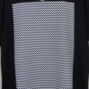 May include: Black t-shirt with a white geometric pattern print. The pattern is a repeating design of small white triangles.