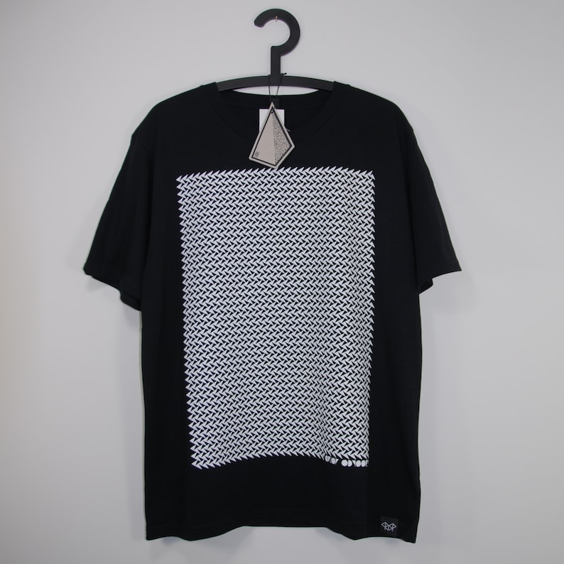 May include: Black t-shirt with a white geometric pattern print. The pattern is a repeating design of small white triangles.