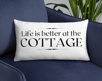 May include: White throw pillow with black text that reads "Life is better at the COTTAGE".