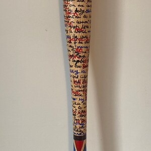 May include: A wooden baseball bat with a grey grip and red, blue and black painted accents. The bat is covered in handwritten text in blue and red ink. The text reads: "shhhinhahan ille baby don't gonna kill for yo phoned in wa houd os and on me ca Baby this went nu to tu Killing ree! Hond Lilo wierde My dou you"