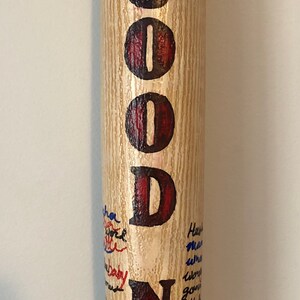 May include: A wooden baseball bat with the word "GOODNIGHT" painted in red and black letters. The bat is covered in blue and black writing.