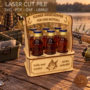 Peut inclure: Un porte-bouteilles en bois avec une poignée contenant six petites bouteilles en verre remplies d'un liquide ambré foncé. Le support présente des gravures laser KLEINER ANGELKOFFER FÜR DEN NOTFALL et Falls mal wieder nichts anbeißt avec un poisson.