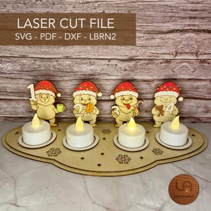 Könnte beinhalten: Ein lasergeschnittener Adventskerzenhalter aus Holz mit vier Cartoon-Kreaturen in Weihnachtsmannmützen, die jeweils eine Zahl von eins bis vier halten. Der Sockel enthält vier weiße LED-Teelichter sowie eingravierte Schneeflocken und Sterne.