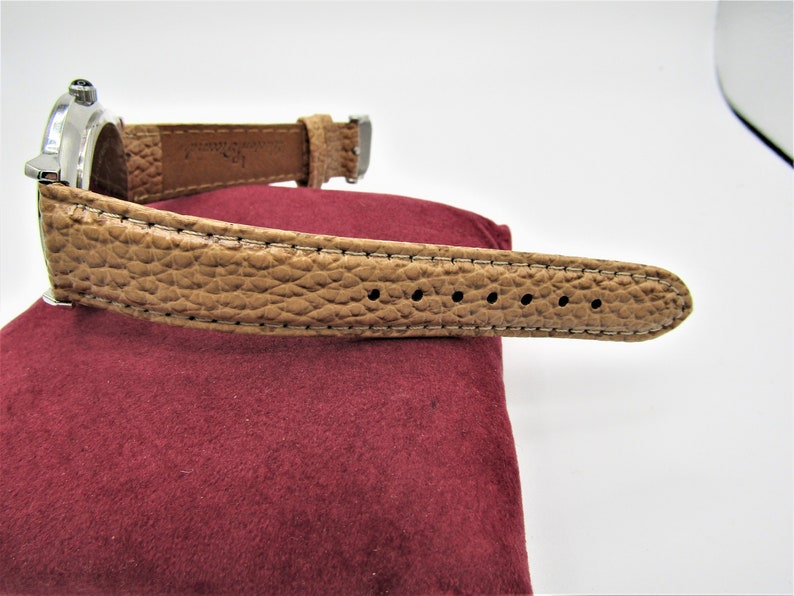 May include: A brown leather watch band with white stitching and a silver buckle.