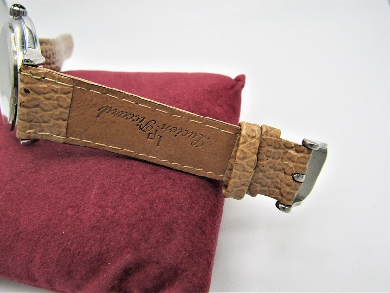 May include: A brown leather watch strap with the text "Lauren, New York" embossed on it.