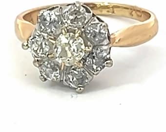 May include: A gold ring with a large, round, clear diamond surrounded by a halo of smaller diamonds.