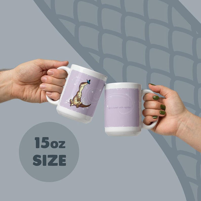 May include: Two white 15oz ceramic mugs featuring a light purple background. One mug displays a brown lizard with a blue butterfly on its nose. The other mug features the text 'Life is better with reptiles' in a white script font on a purple field.