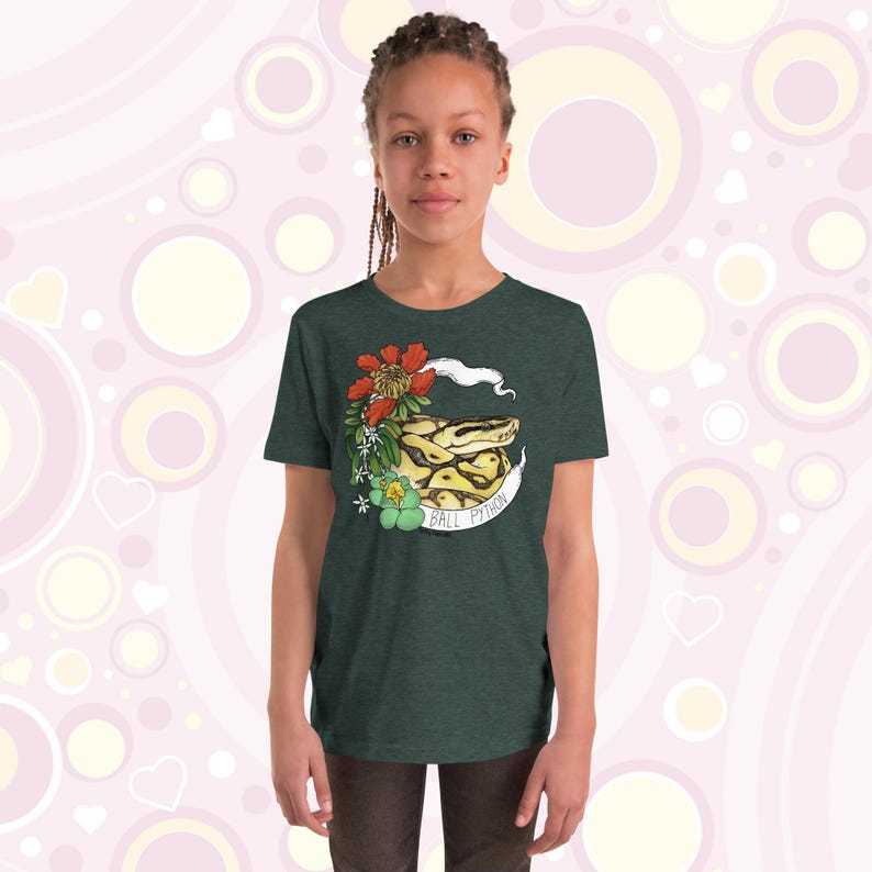Może przedstawiać: Zielony t-shirt z nadrukiem przedstawiającym węża boa dusiciela zwiniętego z kwiatami i tekstem "Ball Python".