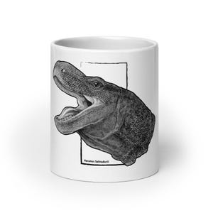 Könnte beinhalten: Ein weißer Keramikbecher mit einer detaillierten schwarz-weißen Illustration eines Krokodilwaran-Kopfes mit geöffnetem Maul. Das Kunstwerk ist in einem dünnen schwarzen Rechteck eingerahmt, und der Text Varanus Salvadorii steht unten.