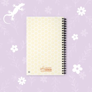 A spiral-bound notebook with a pale yellow and white honeycomb pattern cover, featuring the 'Fatty Pancake' logo at the bottom, displayed on a light purple floral background.