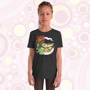 May include: A dark heather grey youth t-shirt featuring a graphic of a ball python snake with flowers and the text "Ball Python".