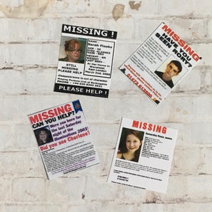 May include: Four missing persons posters with photos and contact information. The posters are on a white brick wall. The posters are for Sarah Flooks, Rory, Charlene, and Samantha Rosie James.