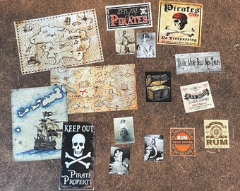 May include: A collection of vintage pirate-themed paper ephemera, including maps, signs, and illustrations. The items feature a skull and crossbones, a pirate ship, a treasure chest, and the text "Beware Pirates", "Pirates Only", "Dead Men Tell No Tales", "Keep Out Pirate Property", "Rum Your Brand", and "Black Bottle Scotch Whisky".