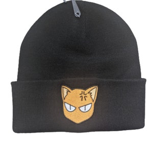 Könnte beinhalten: Schwarze Mütze mit einem gelben und orangefarbenen Comic-Katzenkopf mit dem japanischen Schriftzeichen für "Nord" auf der Stirn.
