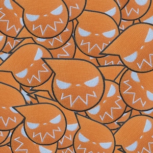 Pode incluir: Uma variedade de patches bordados laranja com um rosto estilizado com olhos brancos e uma boca em zigue-zague. Os patches têm uma cabeça em forma de gota e estão espalhados pela imagem.