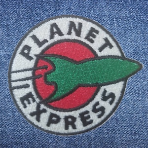 May include: A white, circular patch with the words "Planet Express" in black lettering around a red circle with a green rocket ship inside. The rocket ship has a white trail behind it.