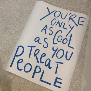 May include: White poster with blue handwritten text that reads "You're only as cool as you treat people".