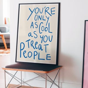 May include: A framed print with a beige background and blue text that reads "You're only as cool as you treat people."