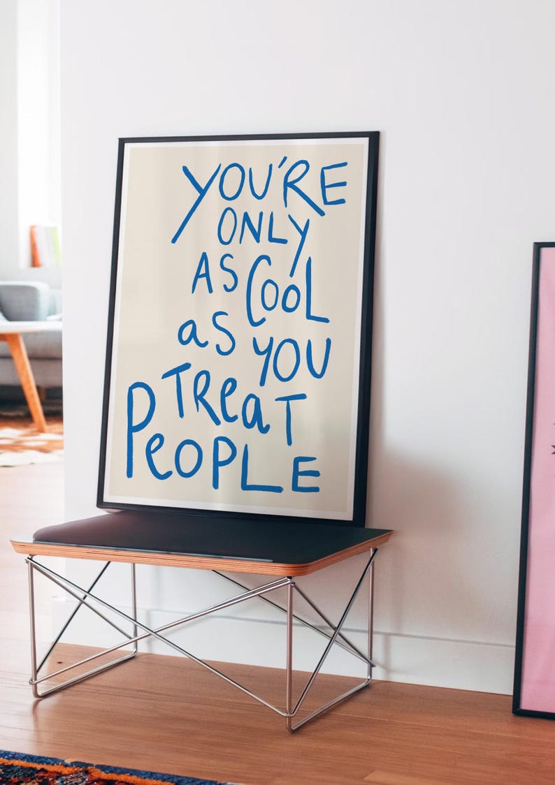 May include: A framed print with a beige background and blue text that reads "You're only as cool as you treat people."