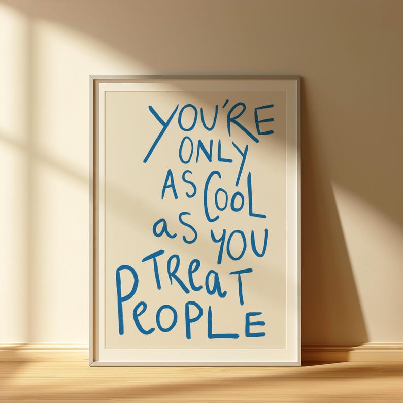 May include: A framed print with a white background and blue text that reads "You're only as cool as you treat people".