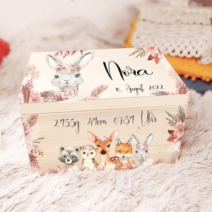 K&ouml;nnte beinhalten: Eine h&ouml;lzerne Erinnerungsbox mit floralem Design und einer Hasenillustration. Die Box ist personalisiert mit dem Namen "Nora", dem Datum "10. August 2022" und den Geburtsdaten "2955g 41cm 07:51 Uhr".