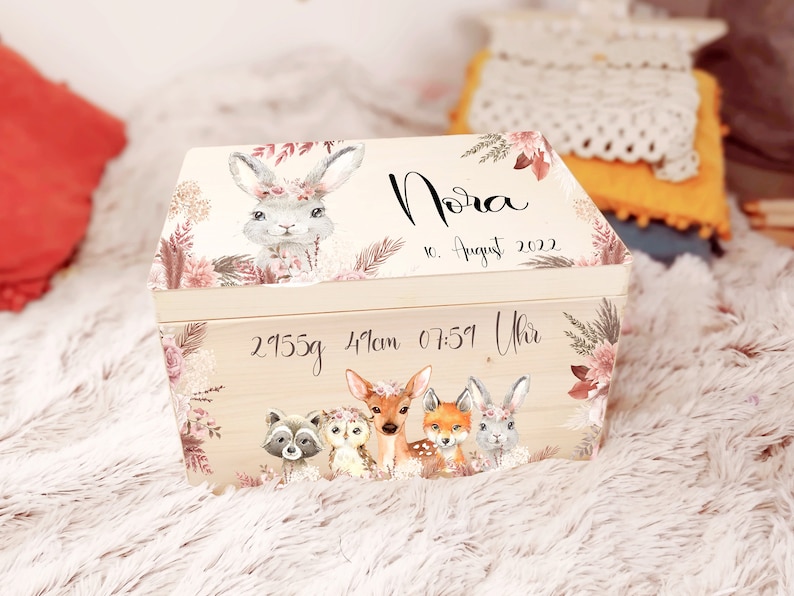 K&ouml;nnte beinhalten: Eine h&ouml;lzerne Erinnerungsbox mit floralem Design und einer Hasenillustration. Die Box ist personalisiert mit dem Namen "Nora", dem Datum "10. August 2022" und den Geburtsdaten "2955g 41cm 07:51 Uhr".